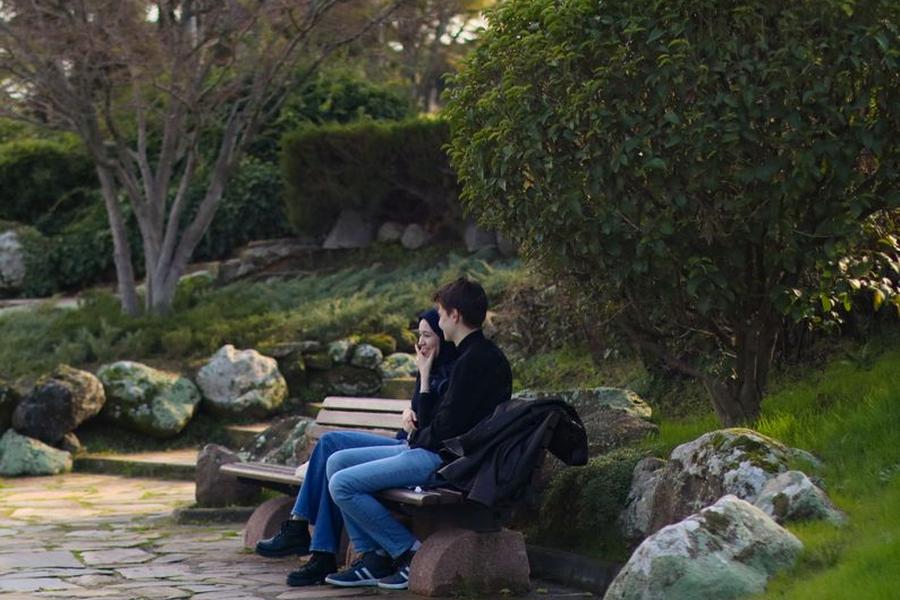 공원 벤치에 나란히 앉아 이야기를 나누는 두 사람
