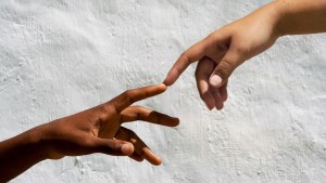 흰 벽을 배경으로 서로를 향해 뻗은 두 사람의 손